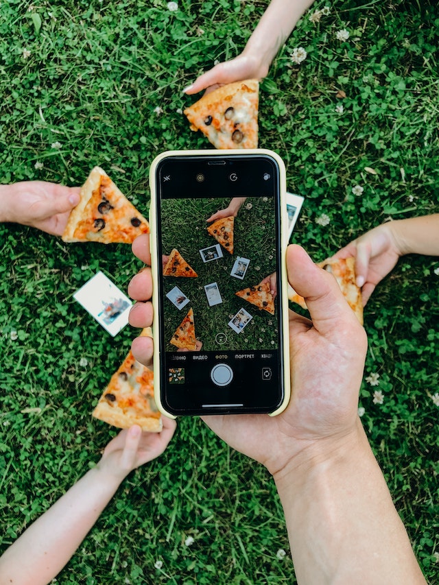 Friends taking an aesthetically pleasing flat-lay photo of their food and Polaroids.