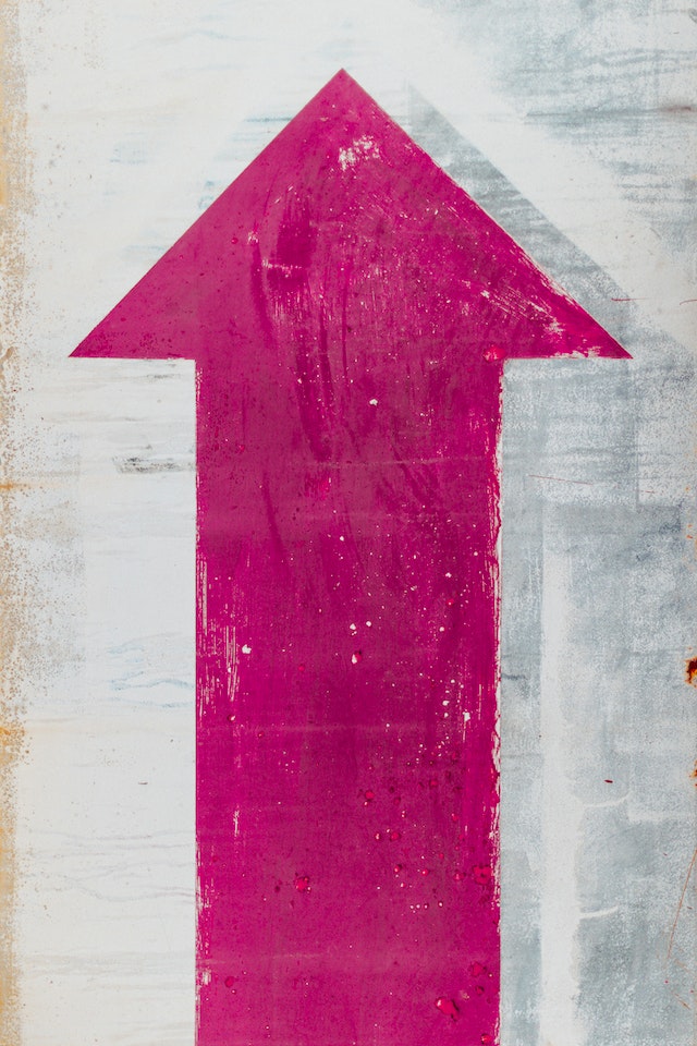 Painted Pink Up Arrow Sign on White Wall