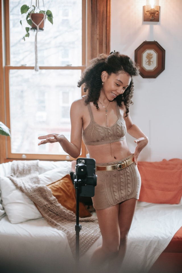 Mulher fotografa uma Instagram Reel das suas roupas novas, que depois se transforma em UGC para a marca de moda de que são provenientes.