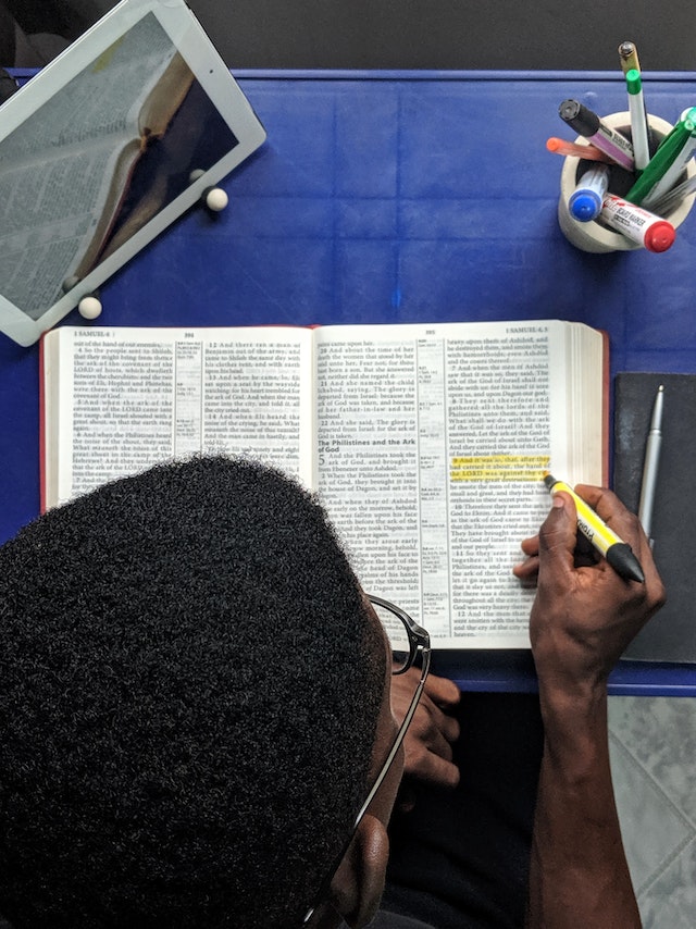 Top view of a man highlighting passages in a book.