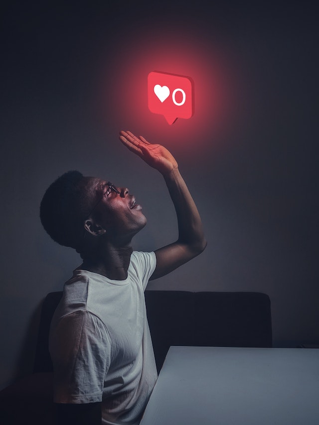 Homme en chemise blanche à col ras du cou tendant la main vers le symbole du like