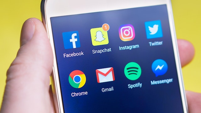 ソーシャルメディアアプリを表示するアンドロイドスマートフォンを持つ不審者。