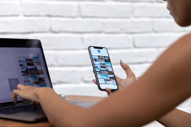 Person sitting at a laptop computer holding a smartphone while planning their affiliate marketing strategy.