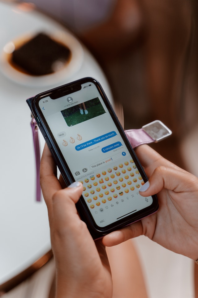 Close-up opname van een persoon die een sms met emoji's verstuurt.