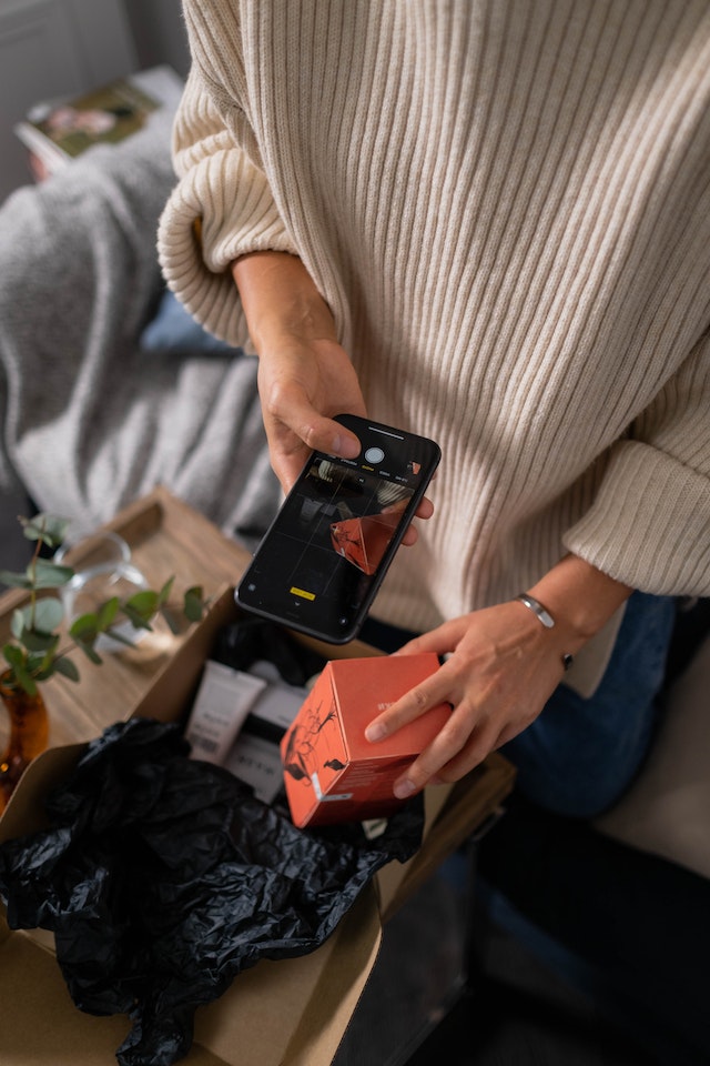 Woman creating user-generated content by taking an unboxing video of her latest purchase.
