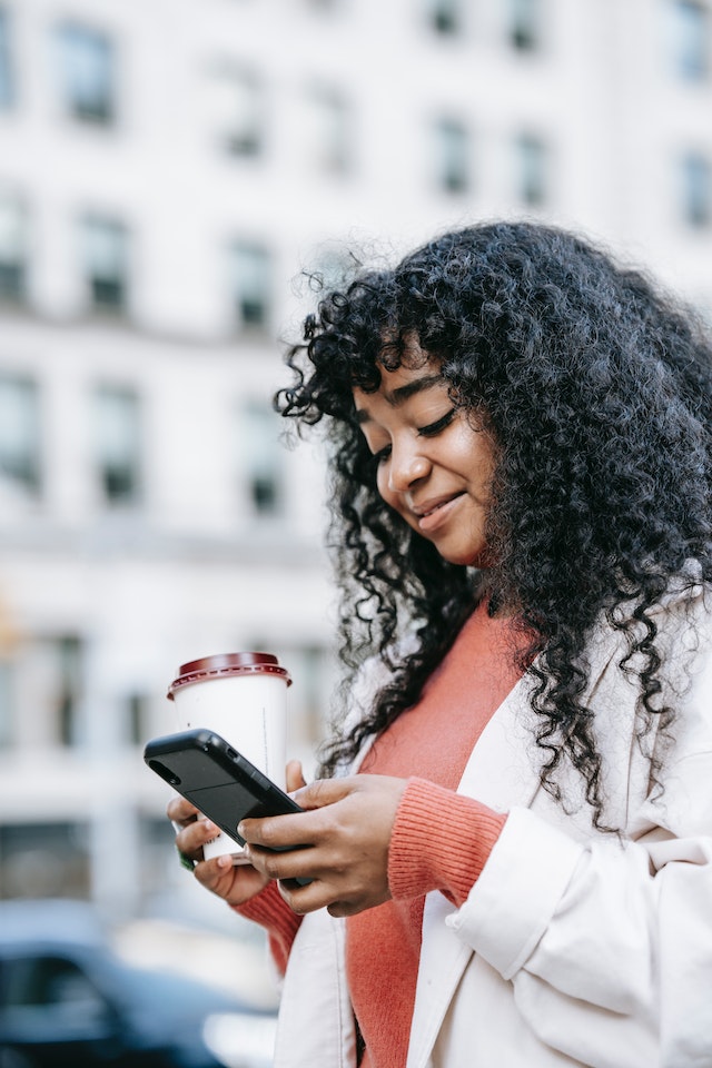 Person in a white long-sleeve shirt holding a silver iPhone.