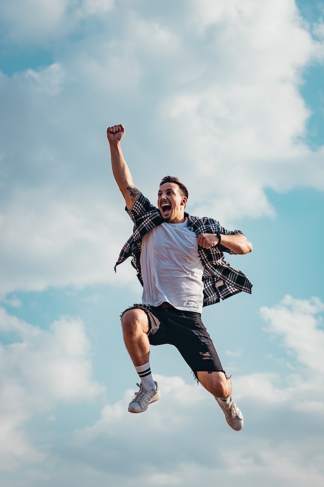 Image of a man jumping into the air with clouds behind him.