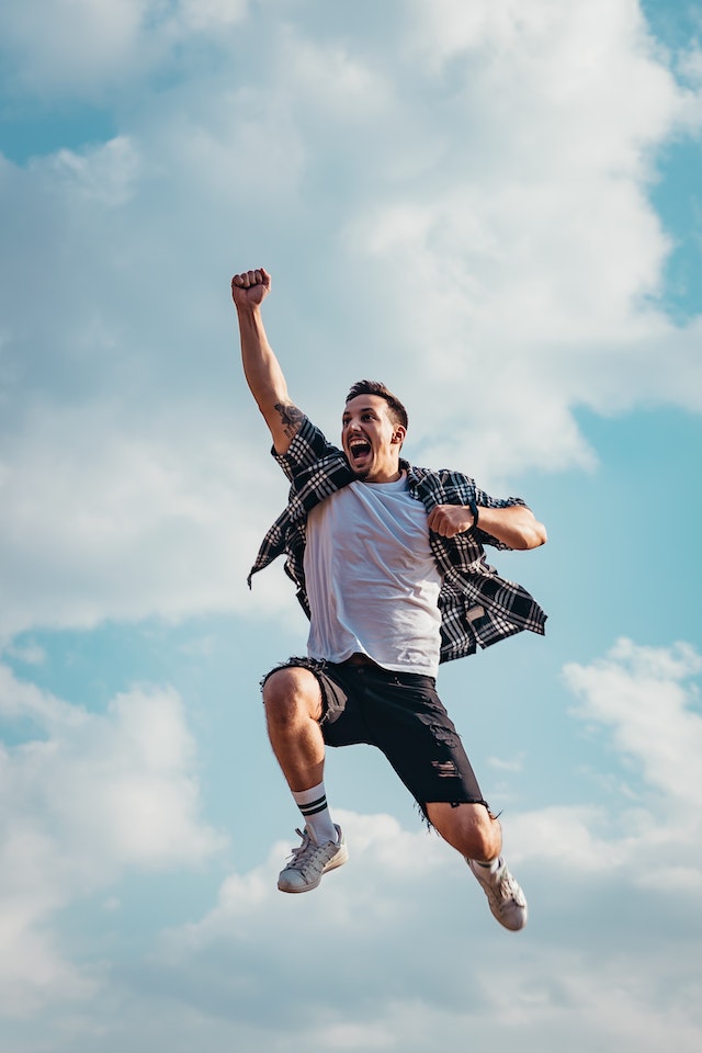 Imagen de un hombre saltando en el aire con nubes detrás de él.