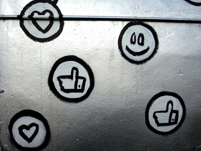 Parede com indicadores de redes sociais: corações, polegares para cima e carinhas sorridentes.