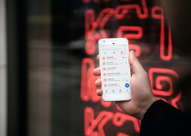 lindsey-lamont-UwnH5jSrdr4-unsplash | Path Social Persona che tiene in mano il proprio telefono mostrando un'app di messaggistica sullo schermo.