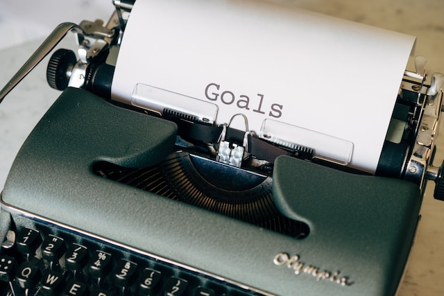 Mașină de scris cu hârtie inserată pe care scrie &quot;Obiective&quot;.