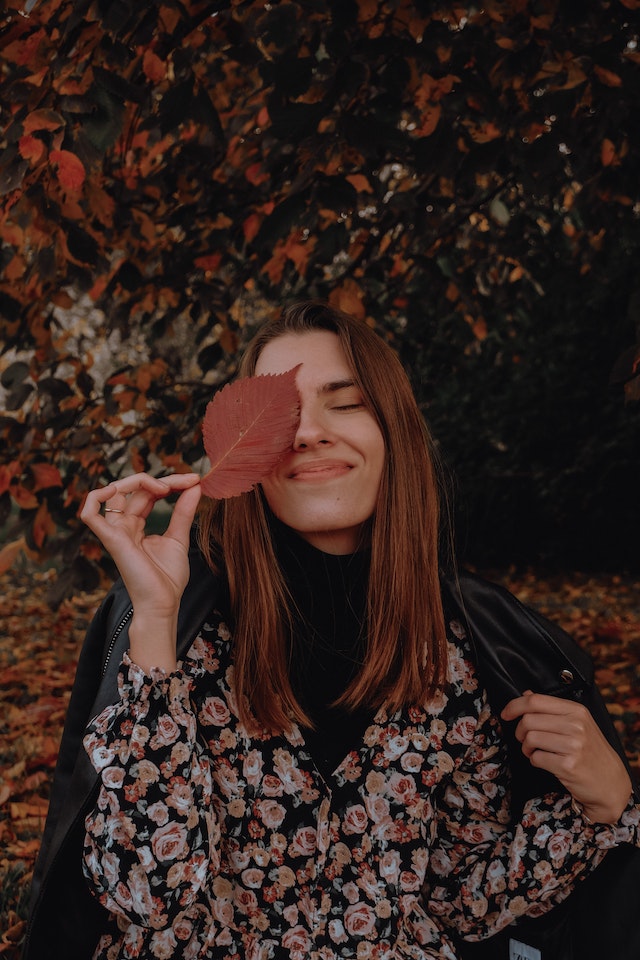 Eine Frau hält ein Blatt, das ihr ein Auge bedeckt