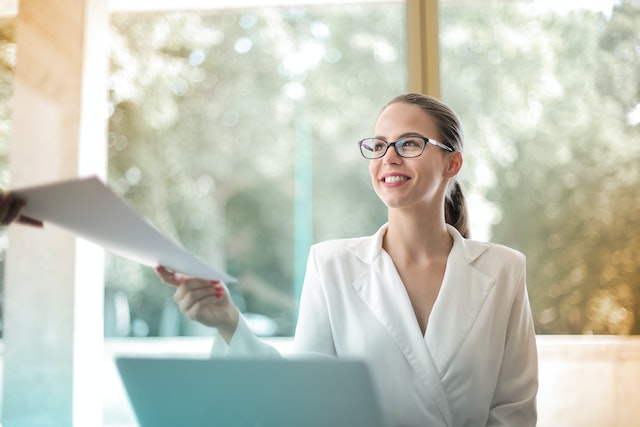 Positive Geschäftsfrau, die in ihrem Büro Papierkram erledigt.