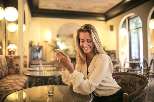 pexels-andrea-piacquadio-3771833 | Path Social Donna seduta a un tavolo che usa il telefono in un ristorante.