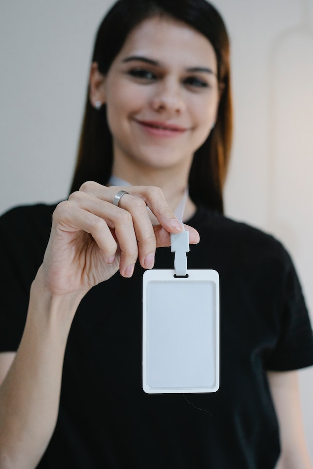 Mujer alegre mostrando una etiqueta con su nombre en blanco.