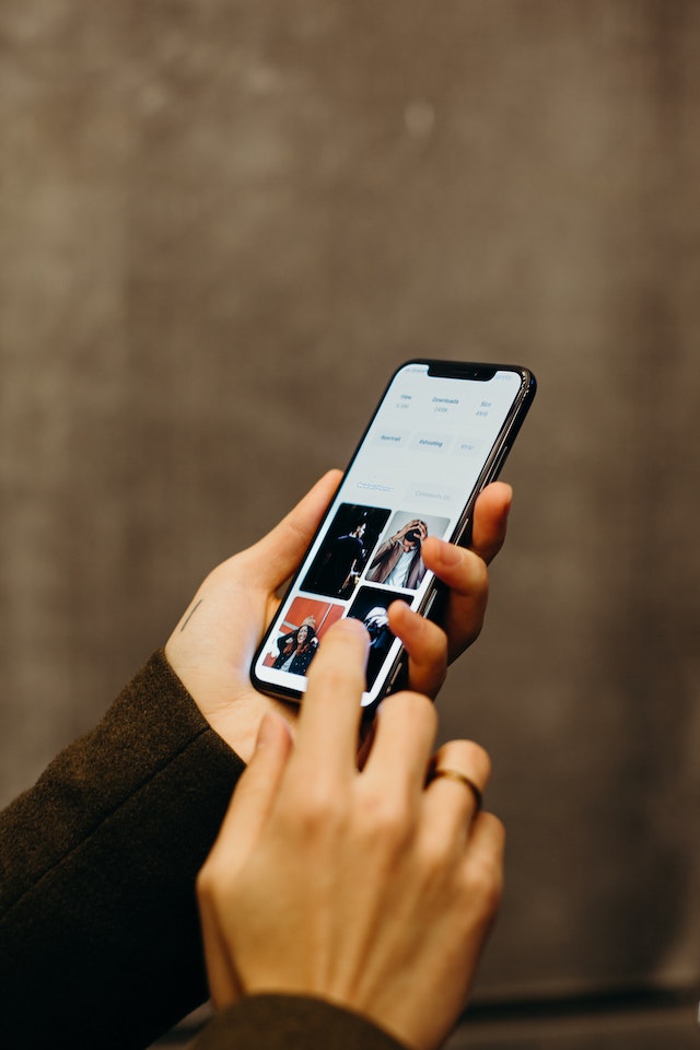 Unseen person holding a black smartphone.