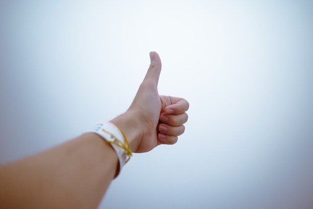 An unseen person doing thumbs-up with a white background.
