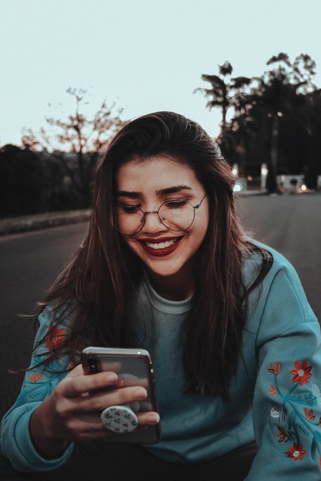 Mujer sonriendo tras recibir un divertido Carrete de su amiga por mensaje directo.