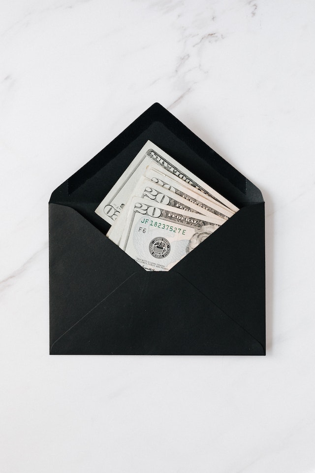 Paper bills visible inside of an open black envelope.