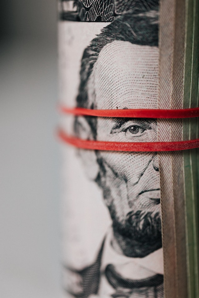 Roll of American dollar banknotes tightened with a rubber band.