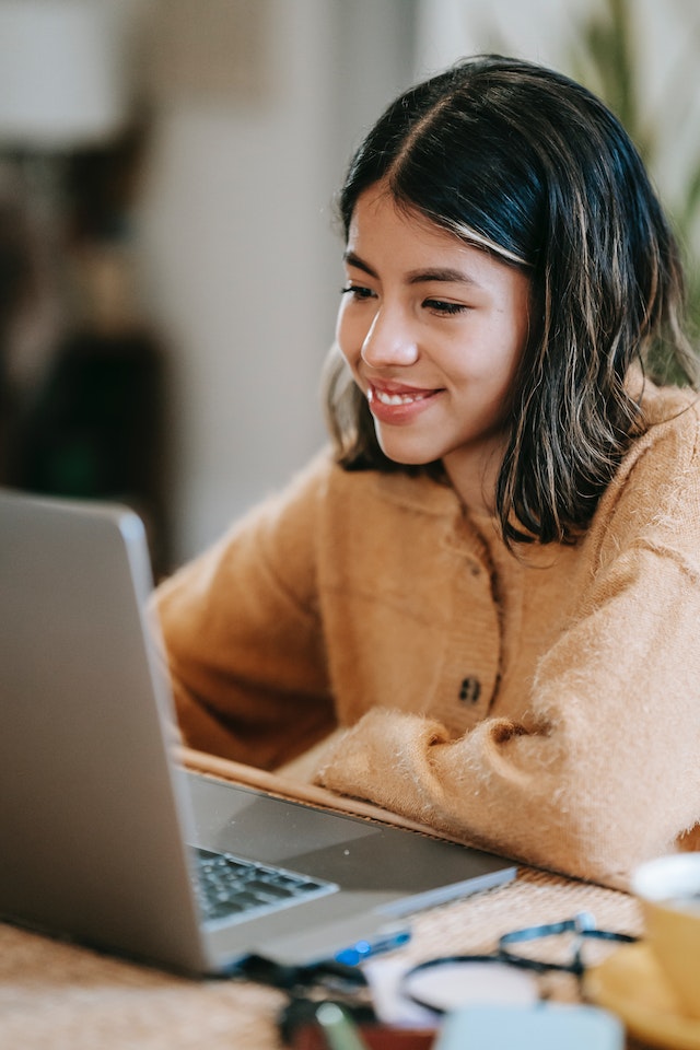 Smiling employee working on laptop in-house.