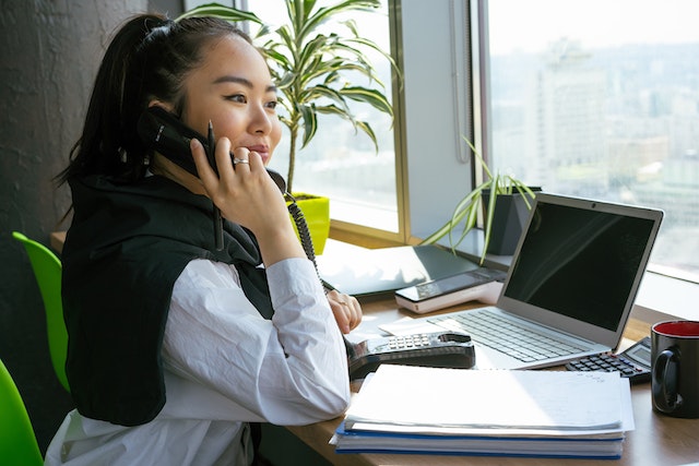 Een vrouw zittend op een stoel terwijl ze een telefoongesprek voert.