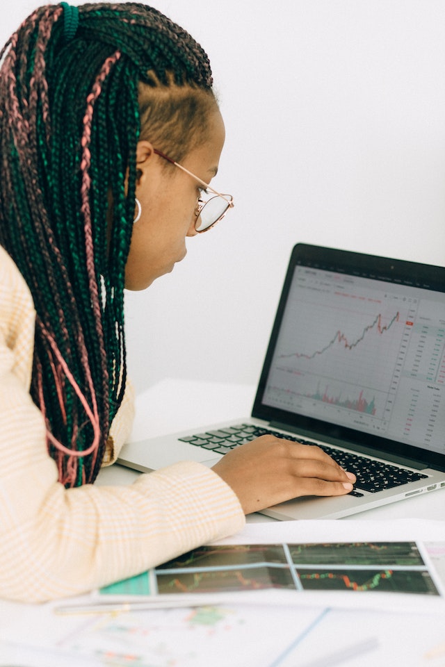 Vrouw in een beige jas analyseert de grafiek op haar laptop