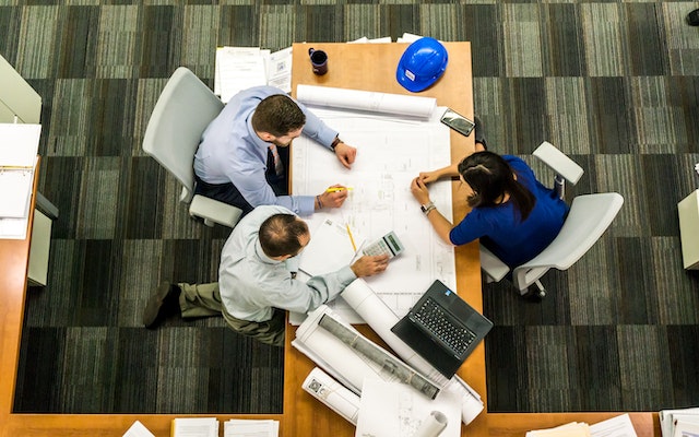 Overhead image of three people sitting at a table during a work meeting.