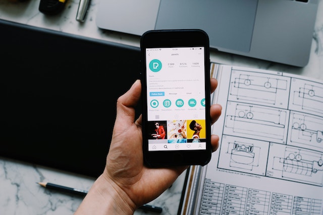 Persona che tiene in mano un telefono e guarda un account di influencer 