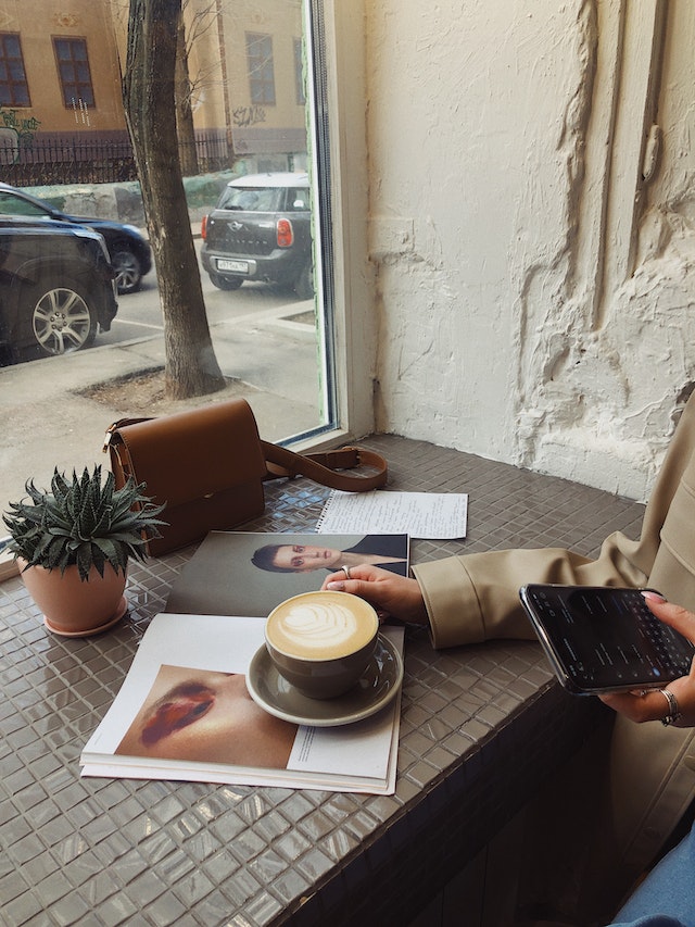 Mujer anónima leyendo una revista en una cafetería.