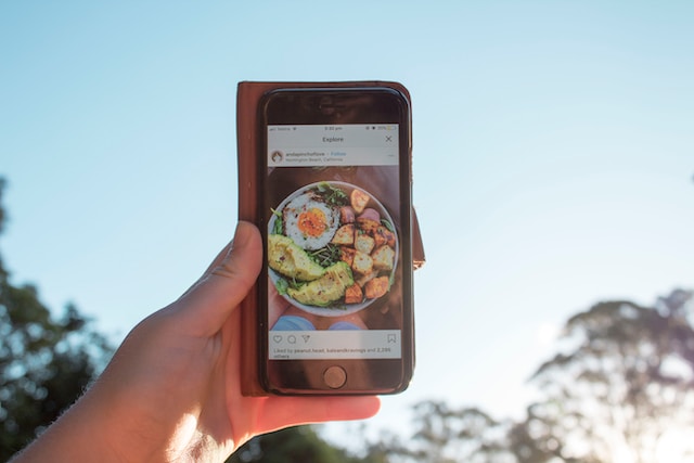 Eine Person hält ein Telefon mit einer geöffneten Instagram Explore-Seite in der Hand.