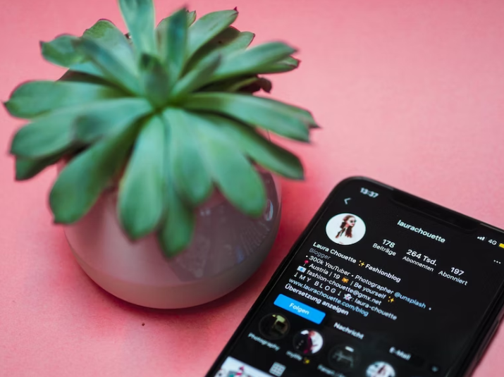 A black iPhone with an influencer's Instagram account on a pink surface. 