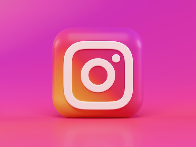 Grafica luminosa del logo Instagram su sfondo rosa sfumato.