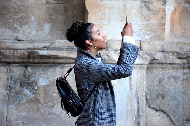 Mulher com um saco a tirar uma fotografia de algo.