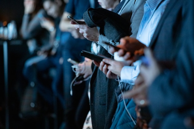 Row of unseen people using their mobile devices.