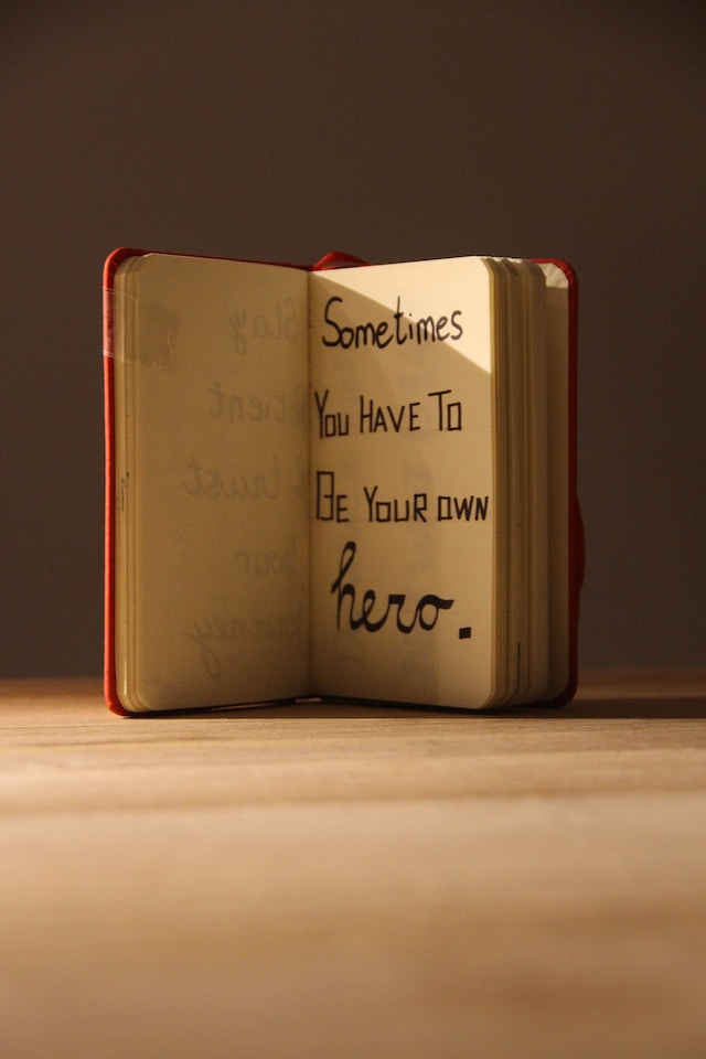 The quote: "Sometimes you have to be your own hero," written on a notebook.