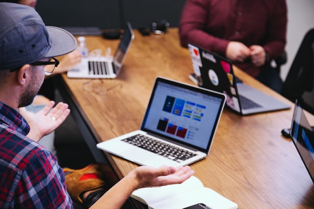 Homme avec une casquette assis devant un ordinateur portable