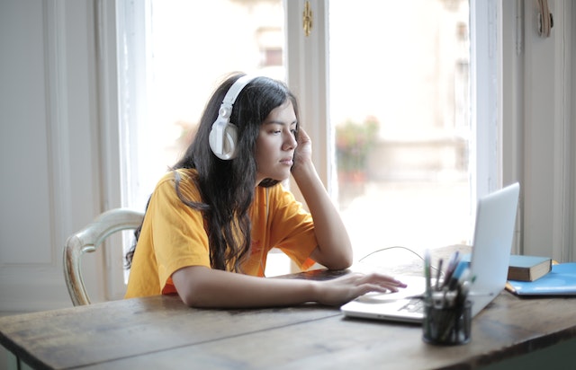 pexels-andrea-piacquadio-3808018 | Path Social Woman wearing headphones sitting in front of a laptop.