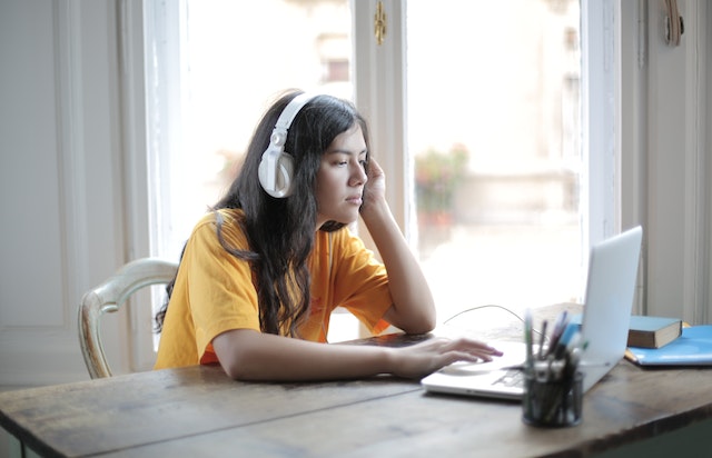 Donna con le cuffie seduta davanti a un computer portatile. 