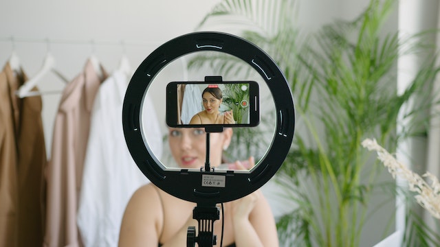 A woman recording herself with her phone inside a ring light.