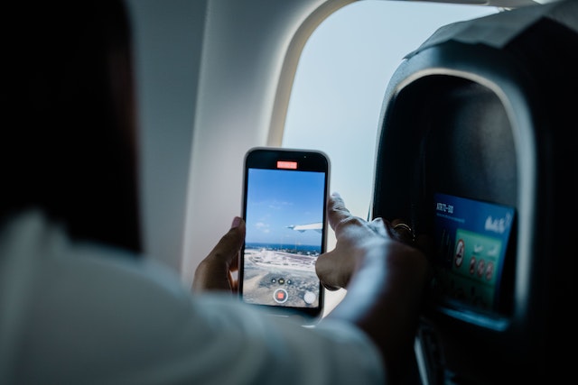 Een meisje maakt een foto vanuit een vliegtuig.