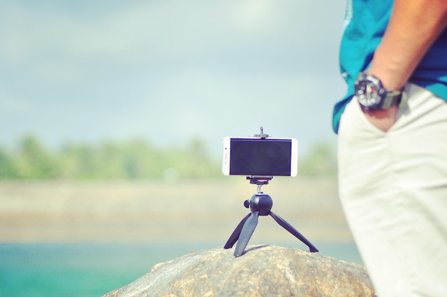 A phone on a tripod and a man standing nearby