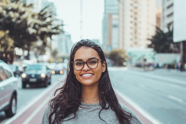 Uma mulher de óculos a sorrir na rua.