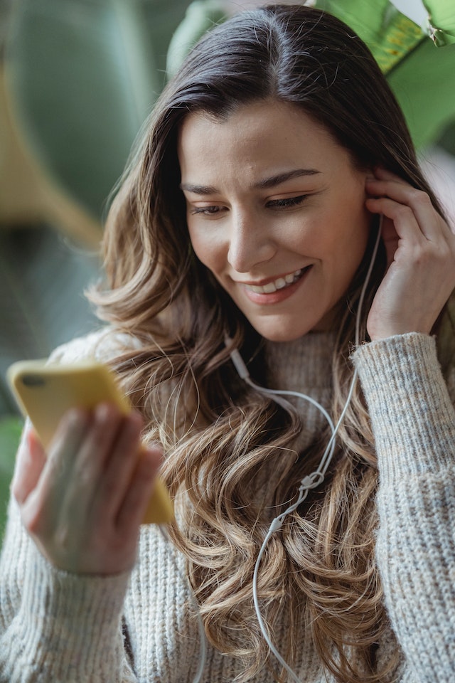 Mulher a sorrir enquanto coloca os auscultadores e conversa em Instagram.