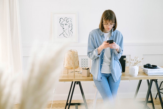 Een Instagram influencer meldt een probleem aan Instagram support op haar smartphone terwijl ze in haar woonkamer staat. 