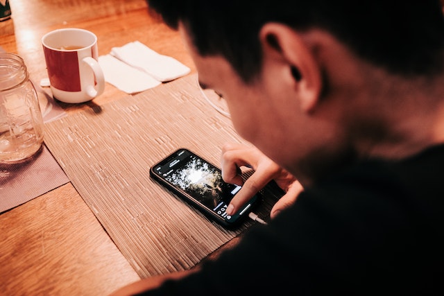 Homem a utilizar o smartphone numa mesa de madeira