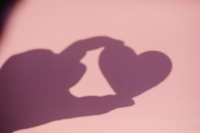A shadow of a person holding a heart to mimic the like icon shape.
