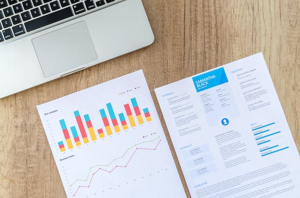 Printed marketing reports on a wooden table next to a computer.