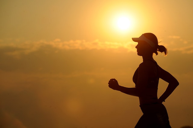 Mujer silueteada mientras corre al atardecer.