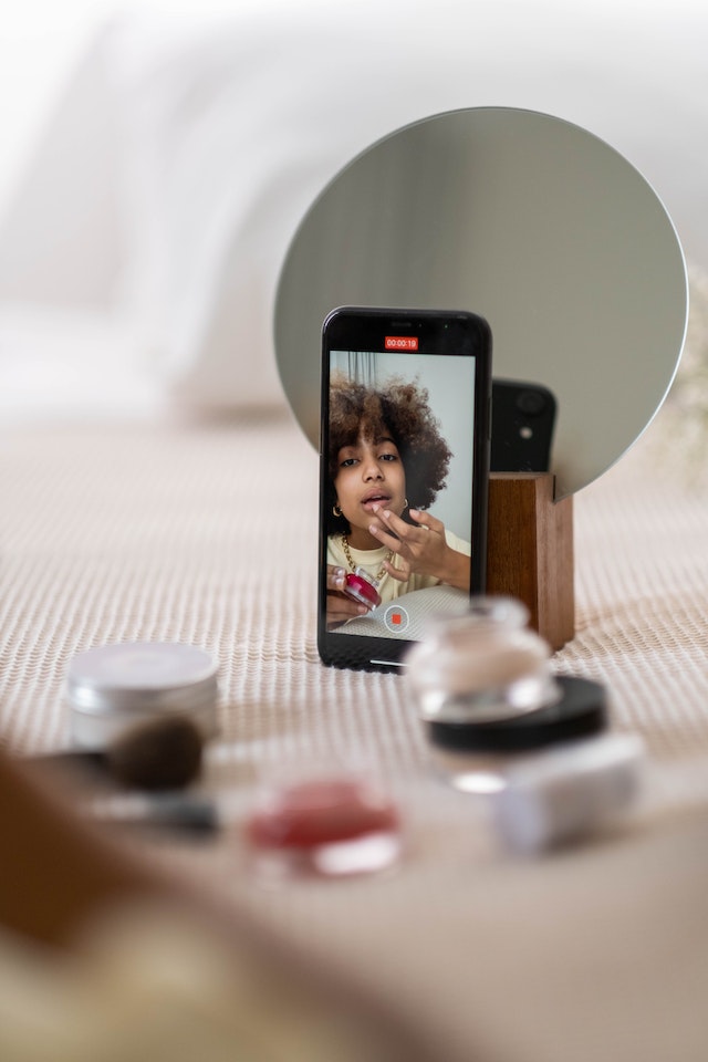 Mujer grabando una reseña de maquillaje para publicarla en las redes sociales.